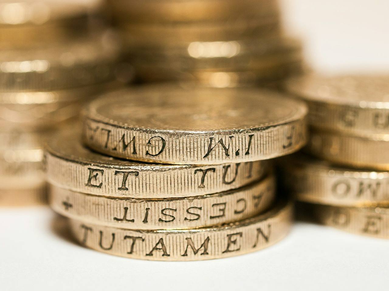 Close-up of stacked British pound coins with lettering on their edges