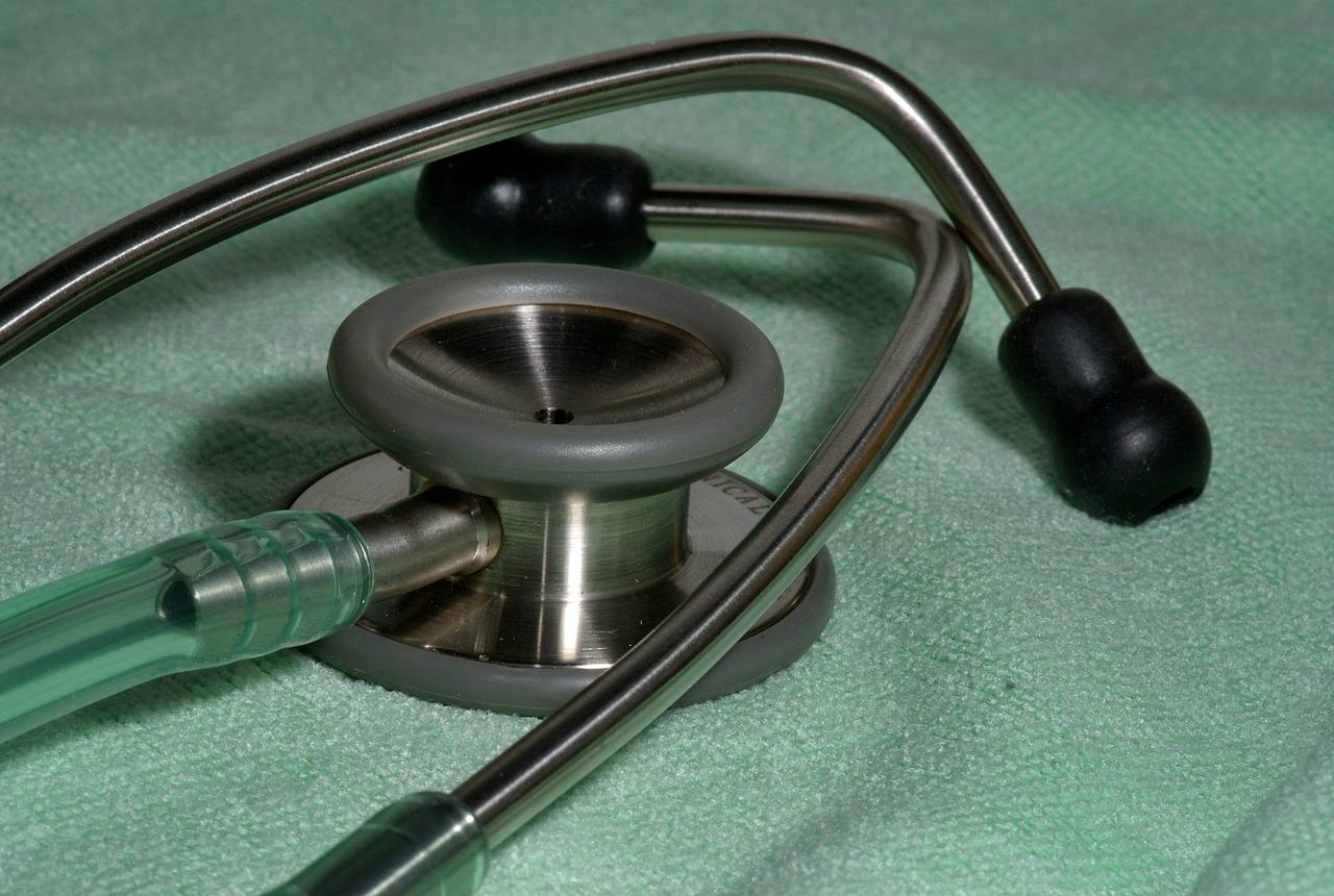 A stainless steel stethoscope lying on a pale green surgical drape